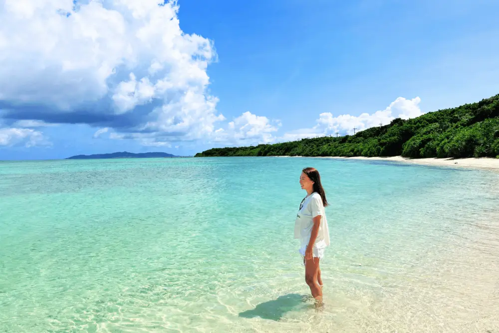 透きとおる海に足をひたして立つ女性